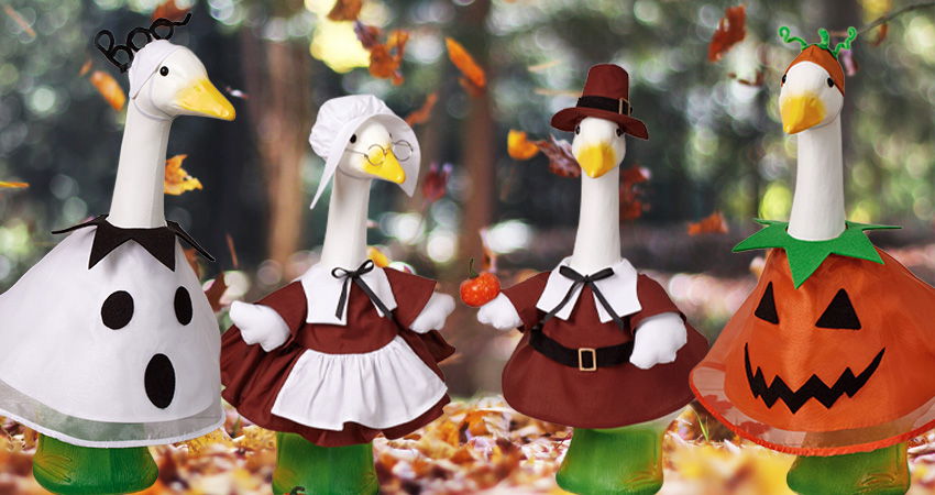 Four decorated geese in seasonal costumes among autumn leaves.