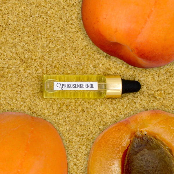Apricot kernel oil and apricots against a sugar background