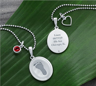 silver oval pendants engraved with a foot, name, and dates