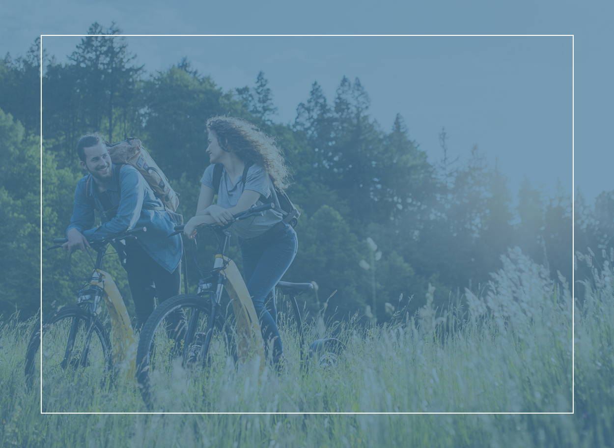 Mladý pár šťastně jede na kole přes travnatou louku; je zjevné, že dobře zvládají svůj zánět spojivek při alergické rýmě