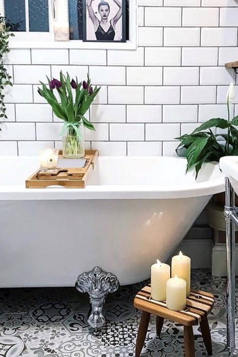 Bath with a bath rack and flowers with LED candles on a stool.