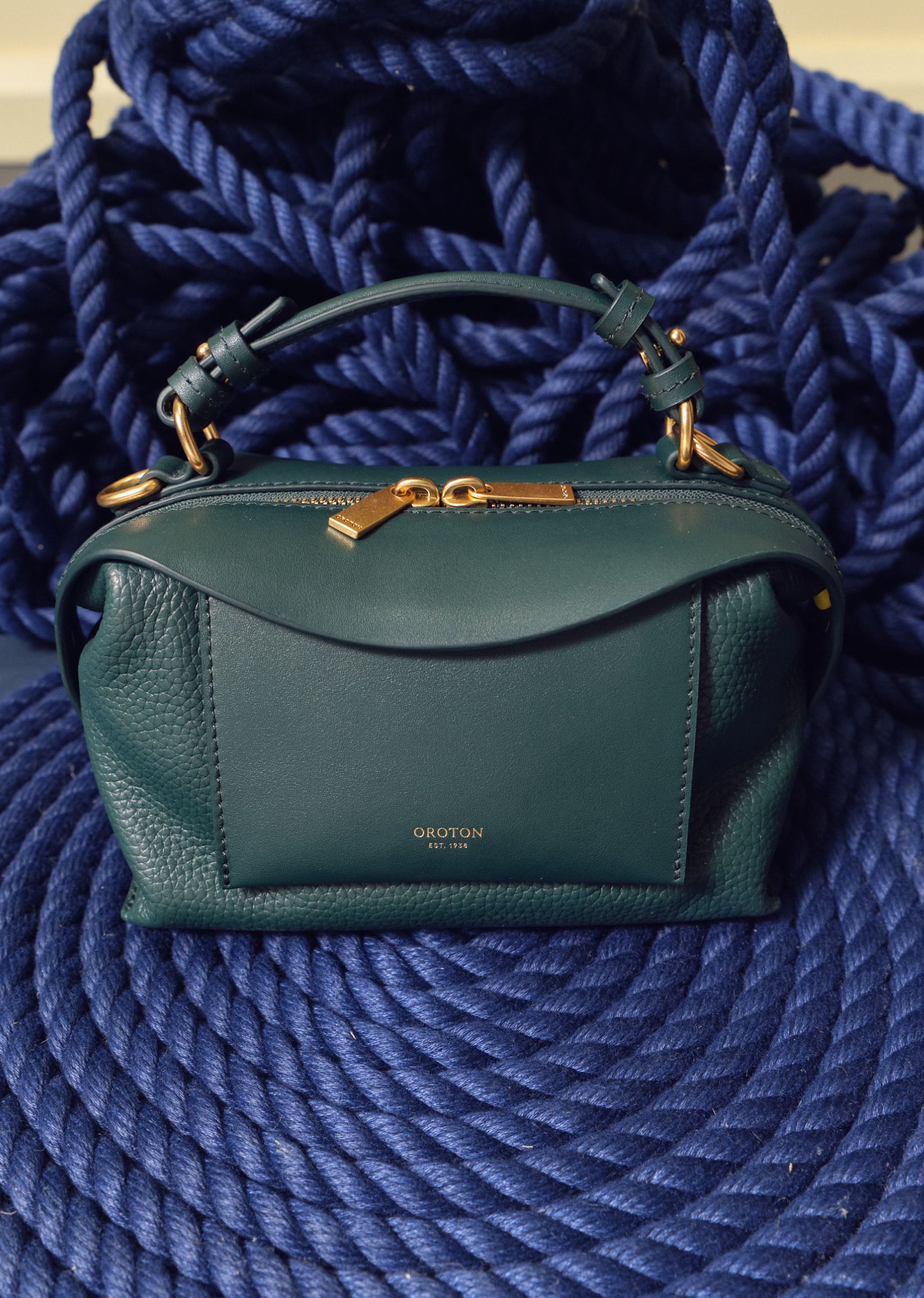 A green handbag resting on blue rope.