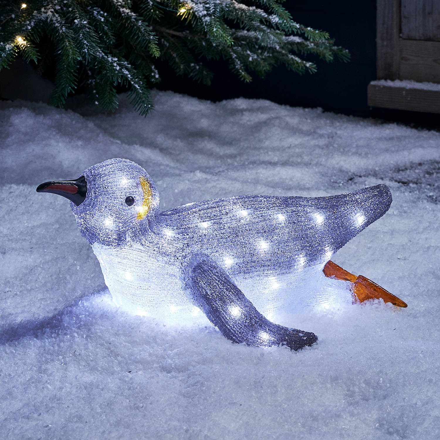 Acrylic penguin figure in an  outdoor snowy setting.