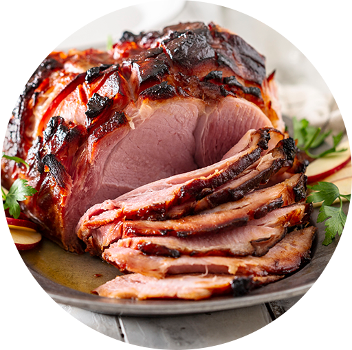 Sliced glazed ham with caramelized edges, served on a platter and garnished with fresh herbs.