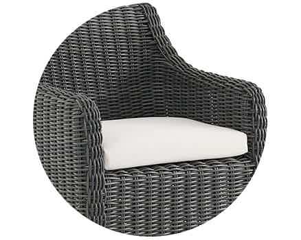 Woven chair with a white cushion, designed for outdoor use.