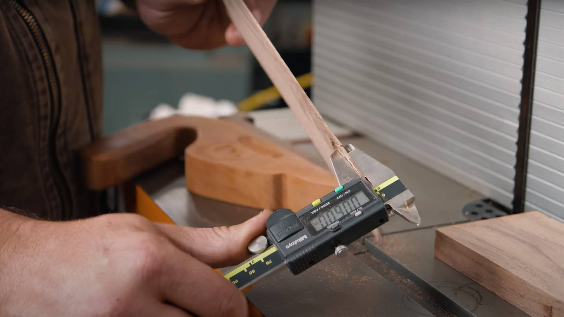 using a pair of digital calipers to measure the thickness of a board