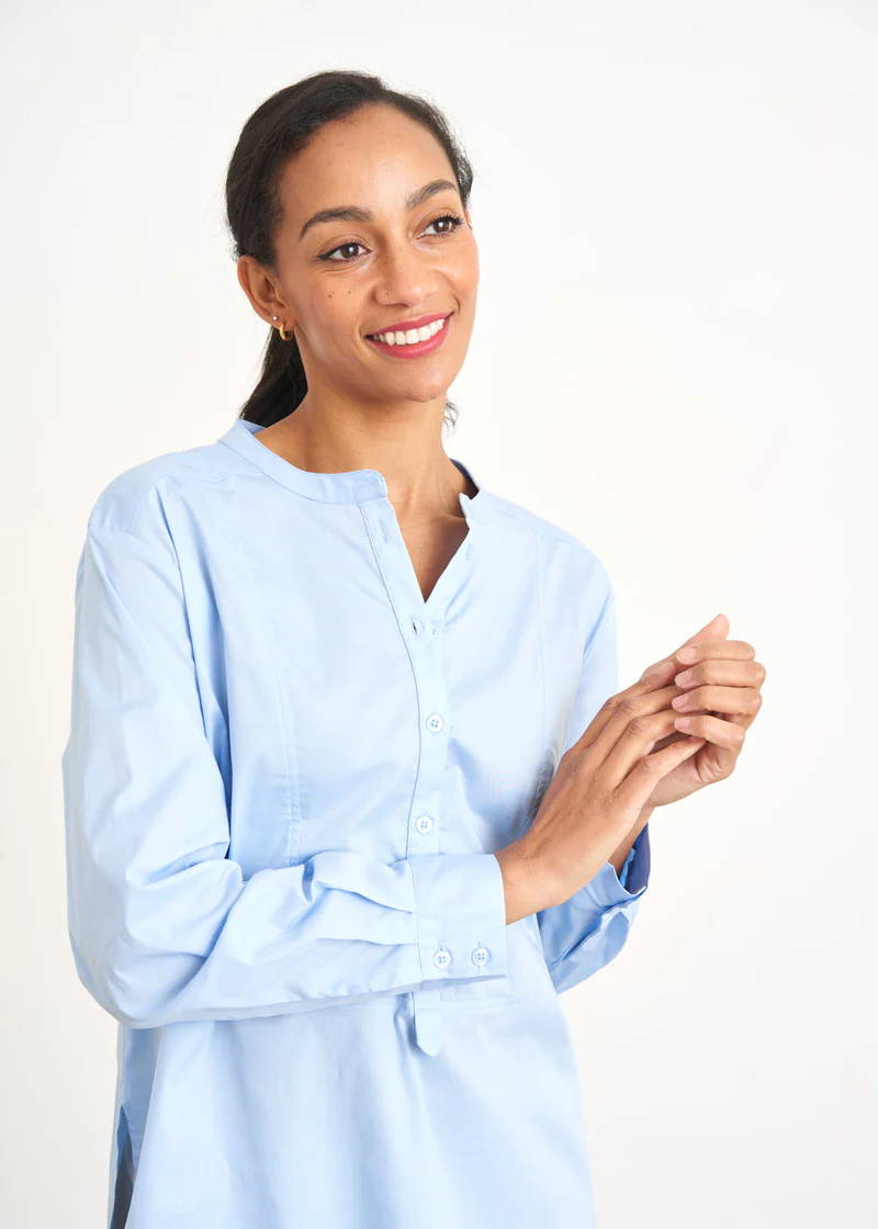 A model wearing a light blue crisp cotton long sleeved shirt with buttoned neckline