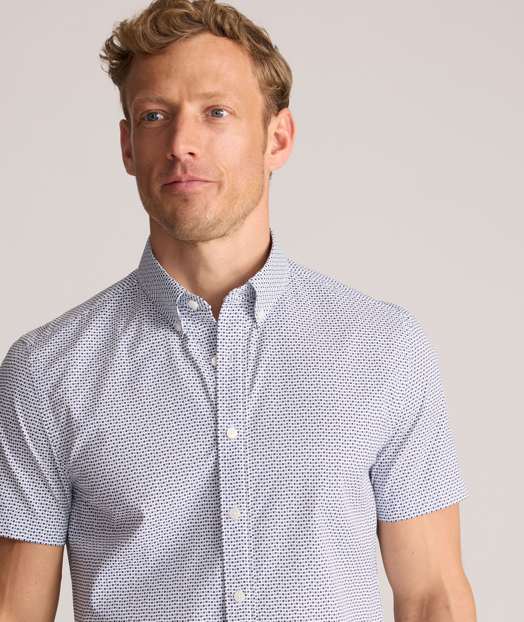 Man in a short-sleeve button-up shirt with a light pattern.