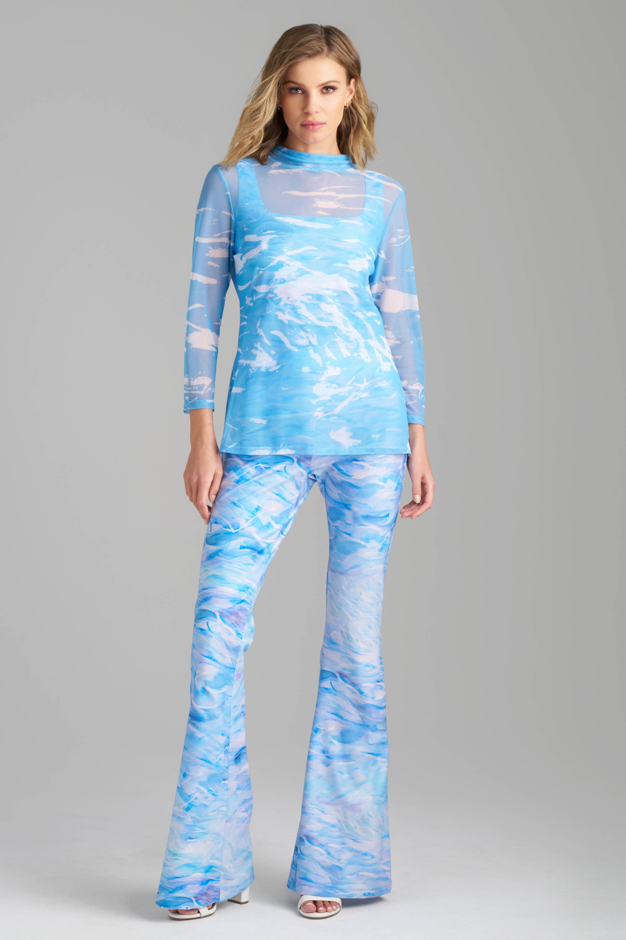 Woman wearing matching blue tank top and pants and mesh cover up set by Ala von Auersperg