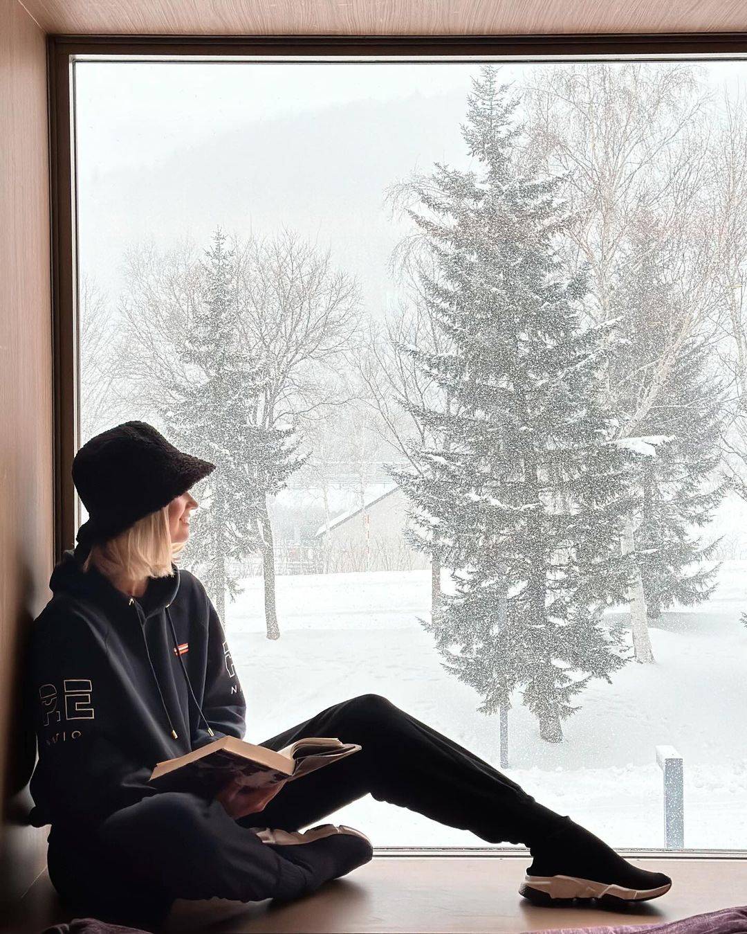 Girl sitting next to a window, with snow outside