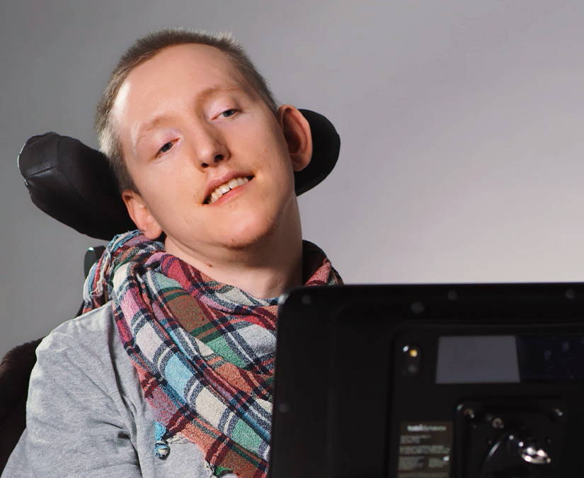 Mann im Rollstuhl mit einem Gerät der Tobii Dynavox I-Serie, um mit seinen Augen zu kommunizieren