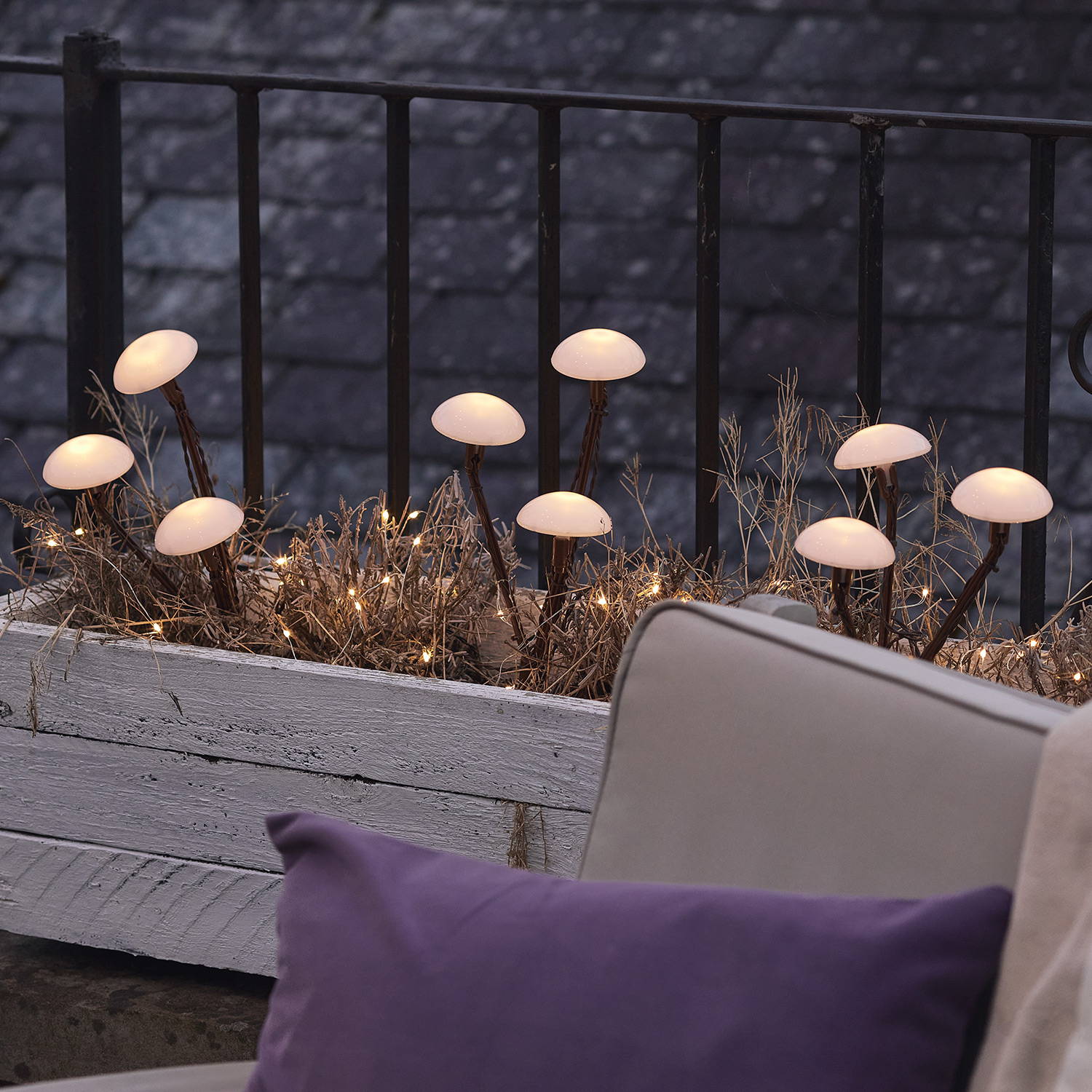 Solar mushroom lights in a flower planter with micro lights weaved through the shrubbery.
