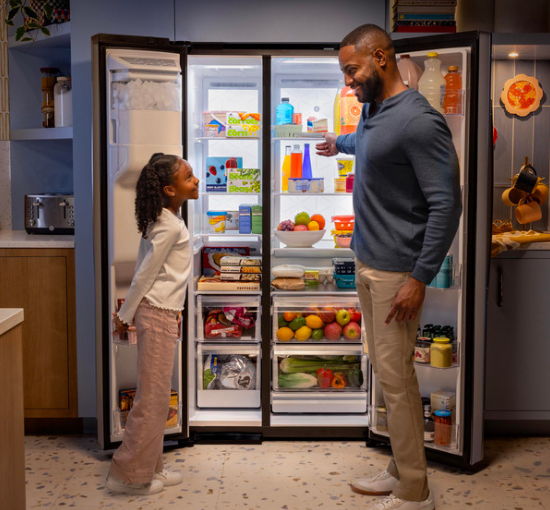 A man and a girl looking at a refrigerator together.