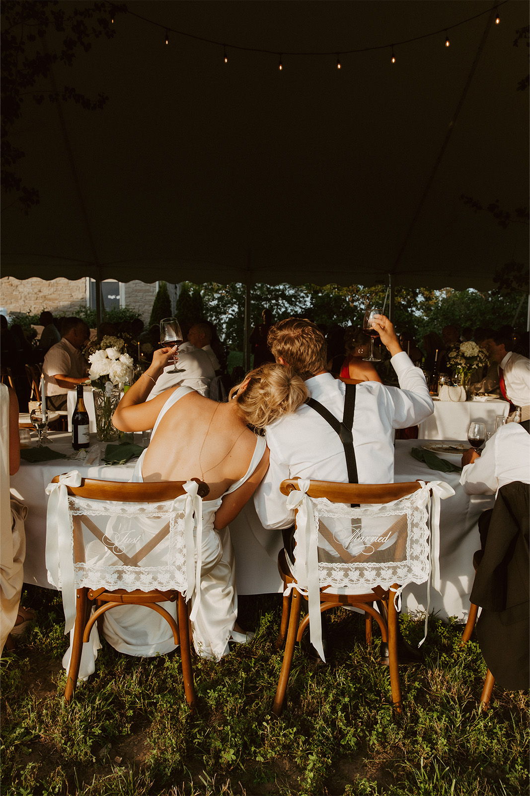 Couple seated at a wedding reception, enjoying the atmosphere under a tent.