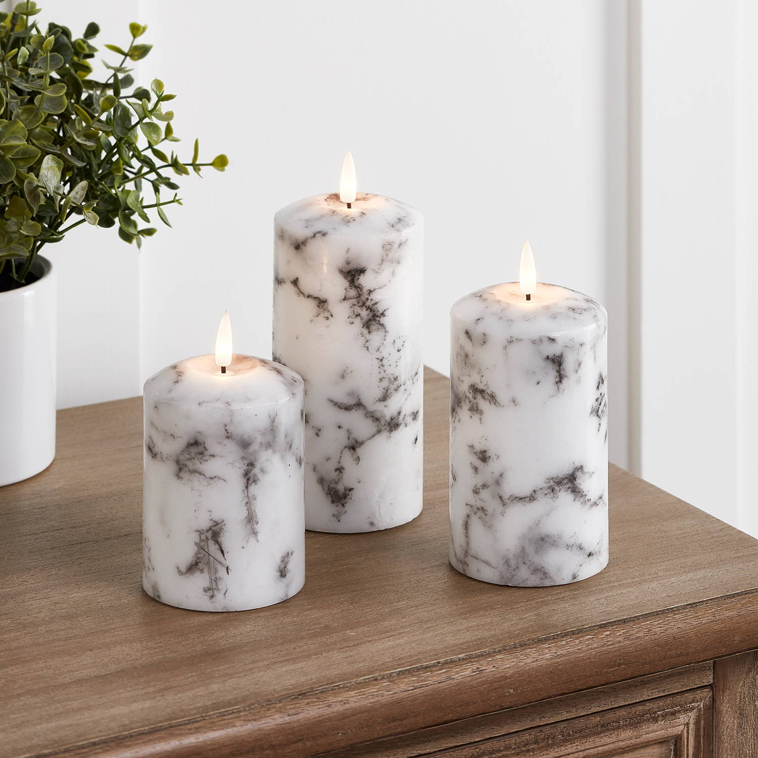 Marble pillar candle trio illuminated on table