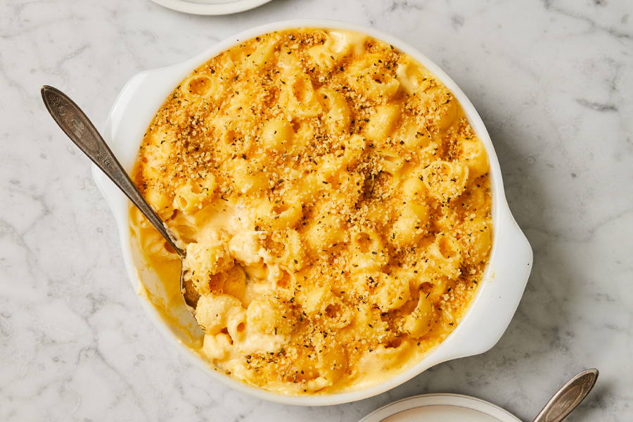 Creamy cheesy shellbow pasta in a round baking dish with toasted breadcrumbs on top.