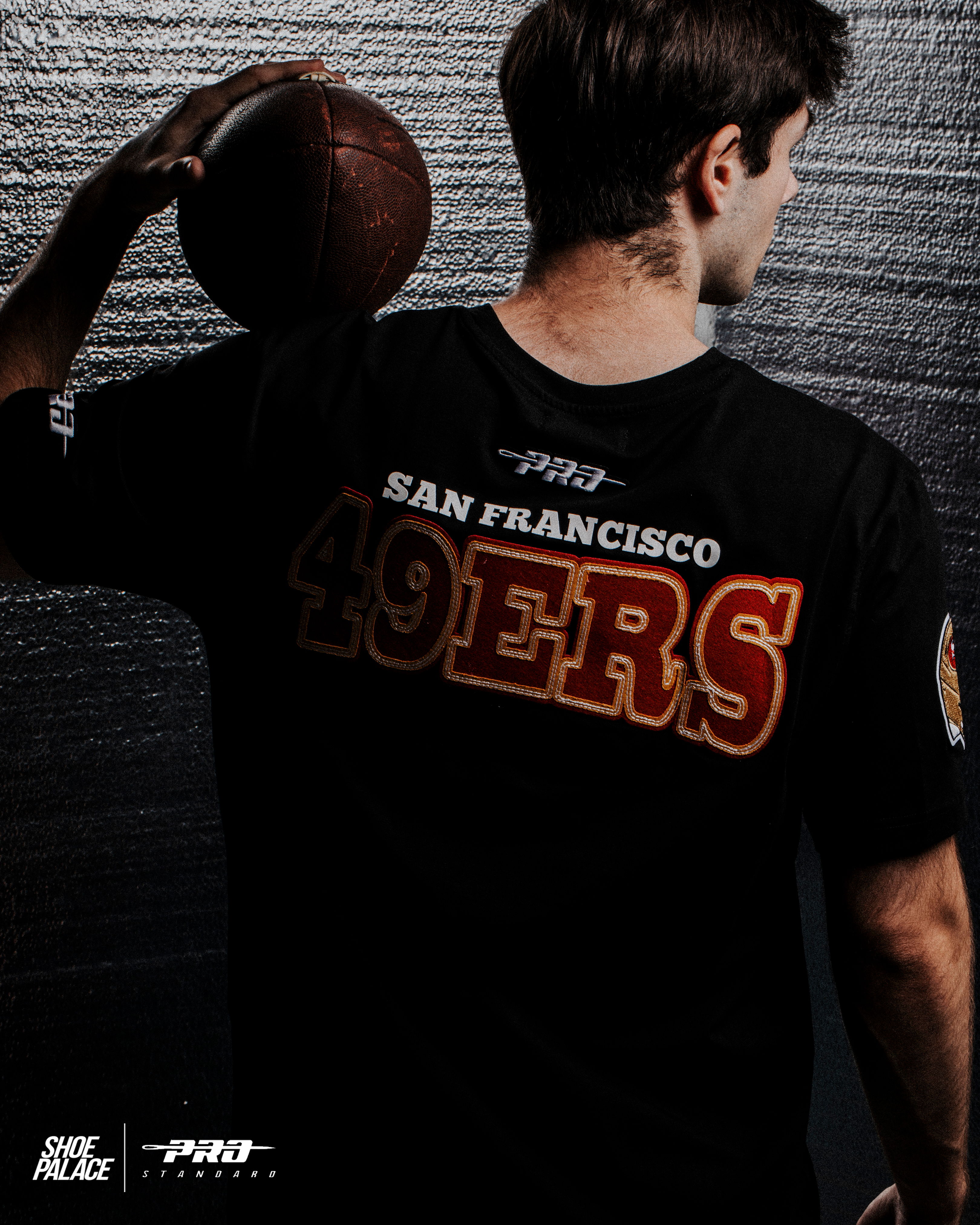 Person wearing a San Francisco 49ers shirt, holding a football.