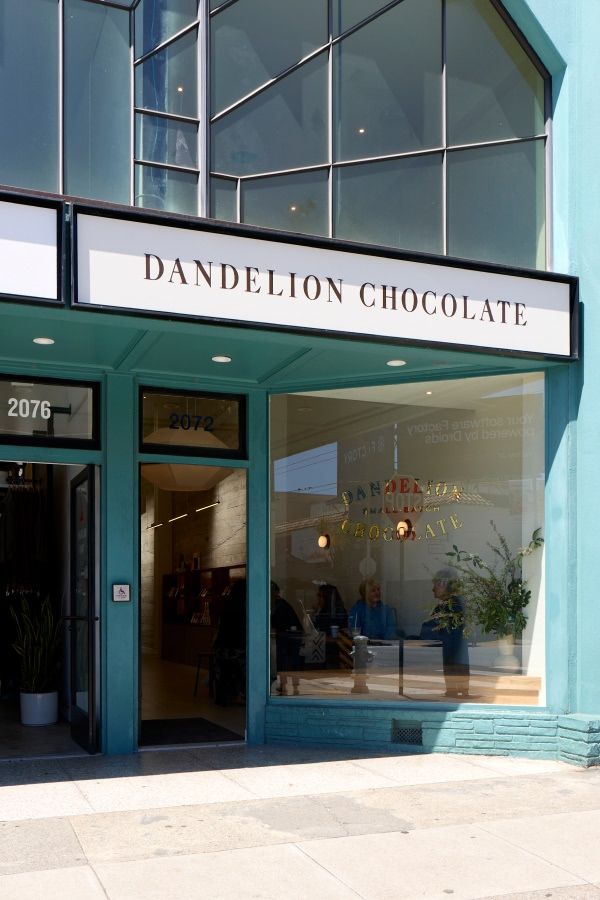 Dandelion Chocolate storefront with large windows and a teal exterior.