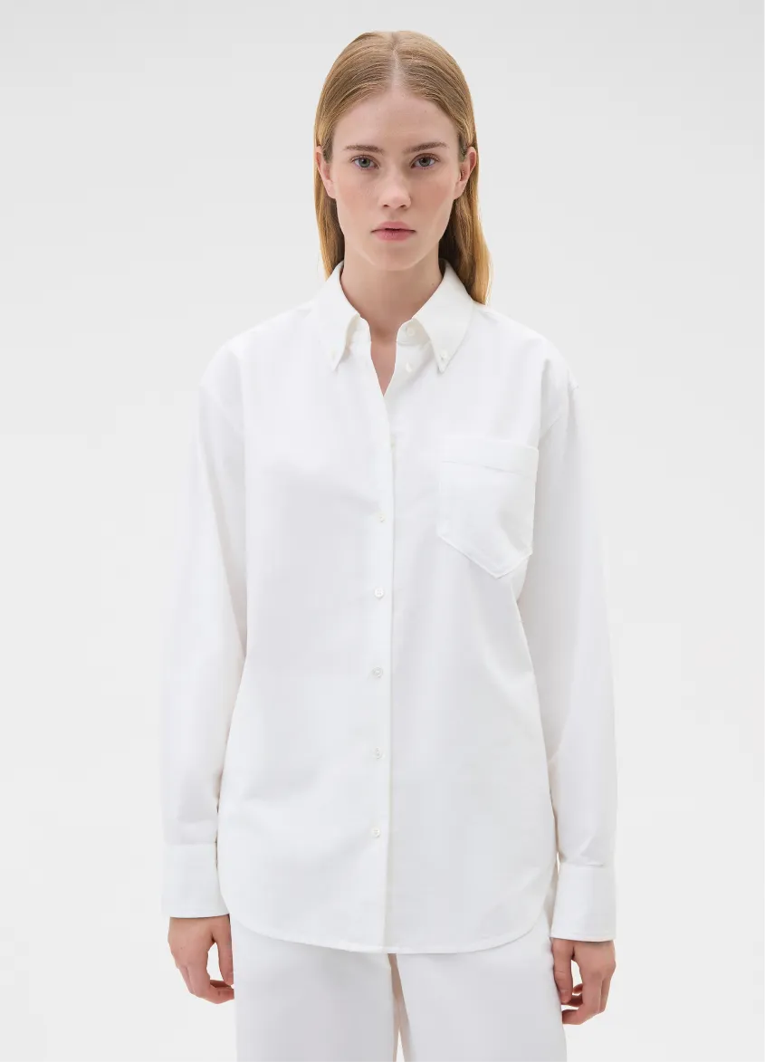 Model wearing a white button-up shirt with a pocket.