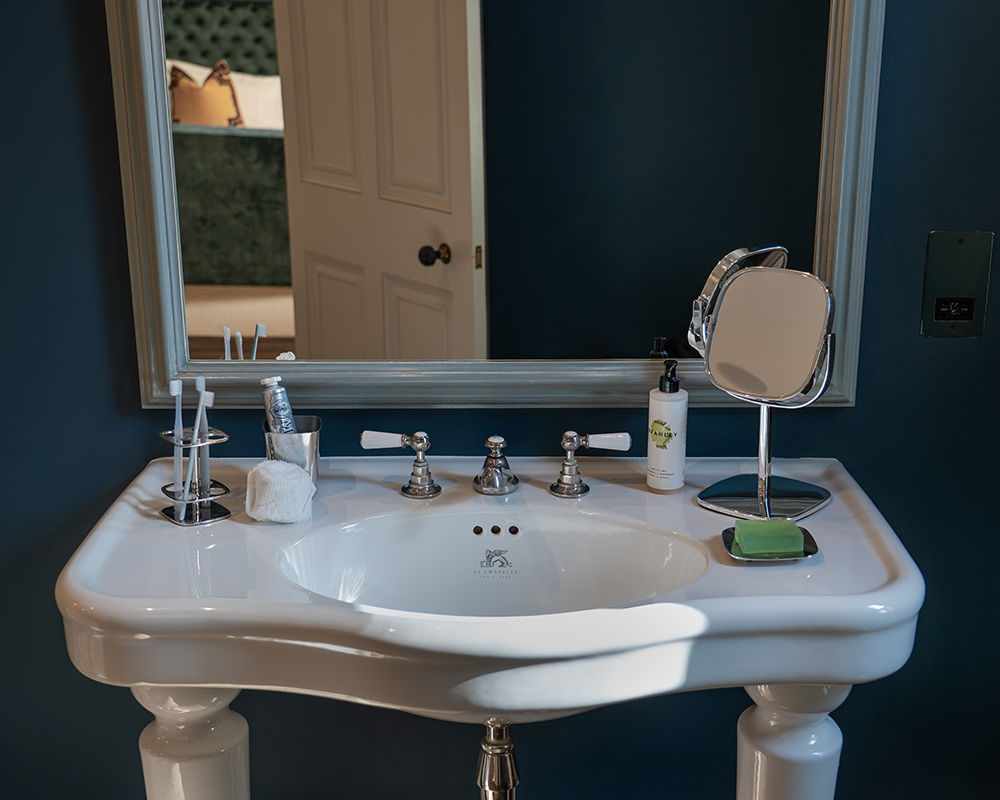 A bathroom sink with a mirror, soap, and toiletries on a countertop.