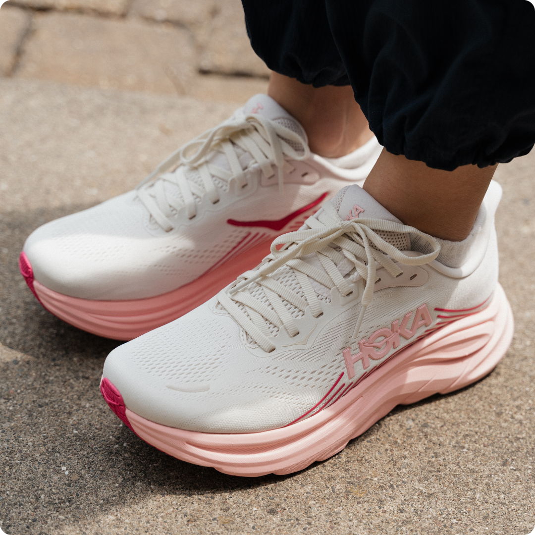 White and pink athletic shoes worn on a sidewalk.