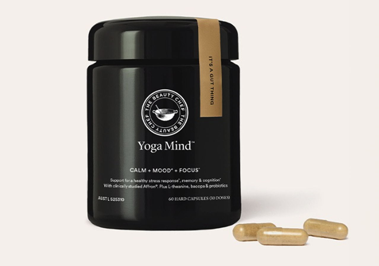Black jar of yoga supplements with two capsules beside it.
