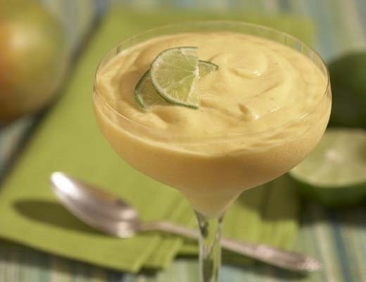 Mango mousse dessert garnished with lime slice in a glass.