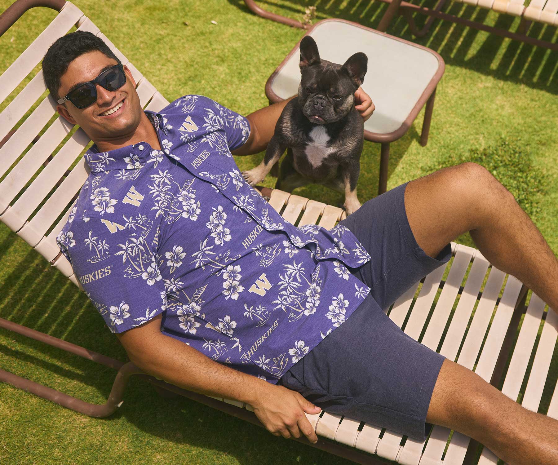 A person in sunglasses relaxing on a lounge chair with a dog.