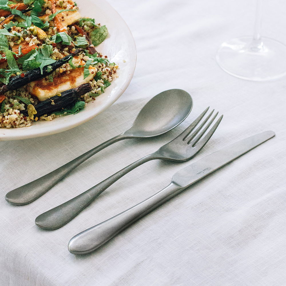 Quinton Vintage cutlery set beside a plate of salad on a table.