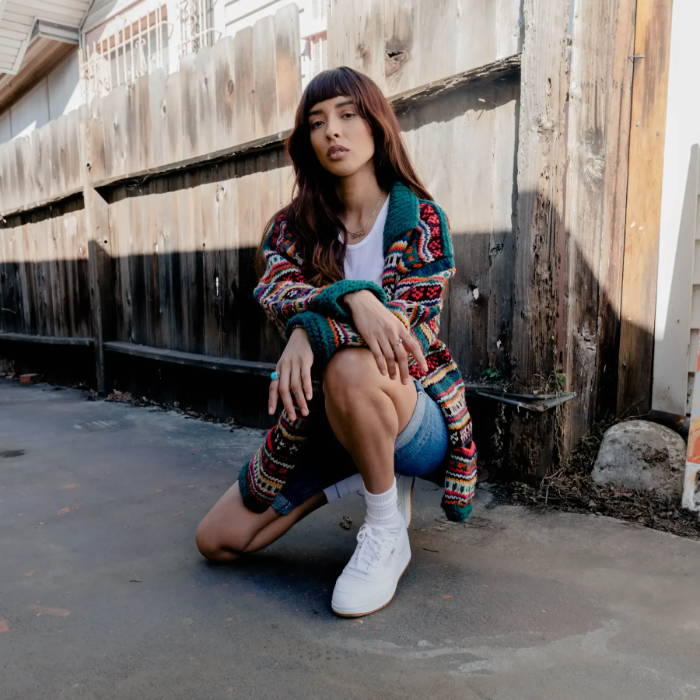 female model squatting near fence wearing reebok sneakers