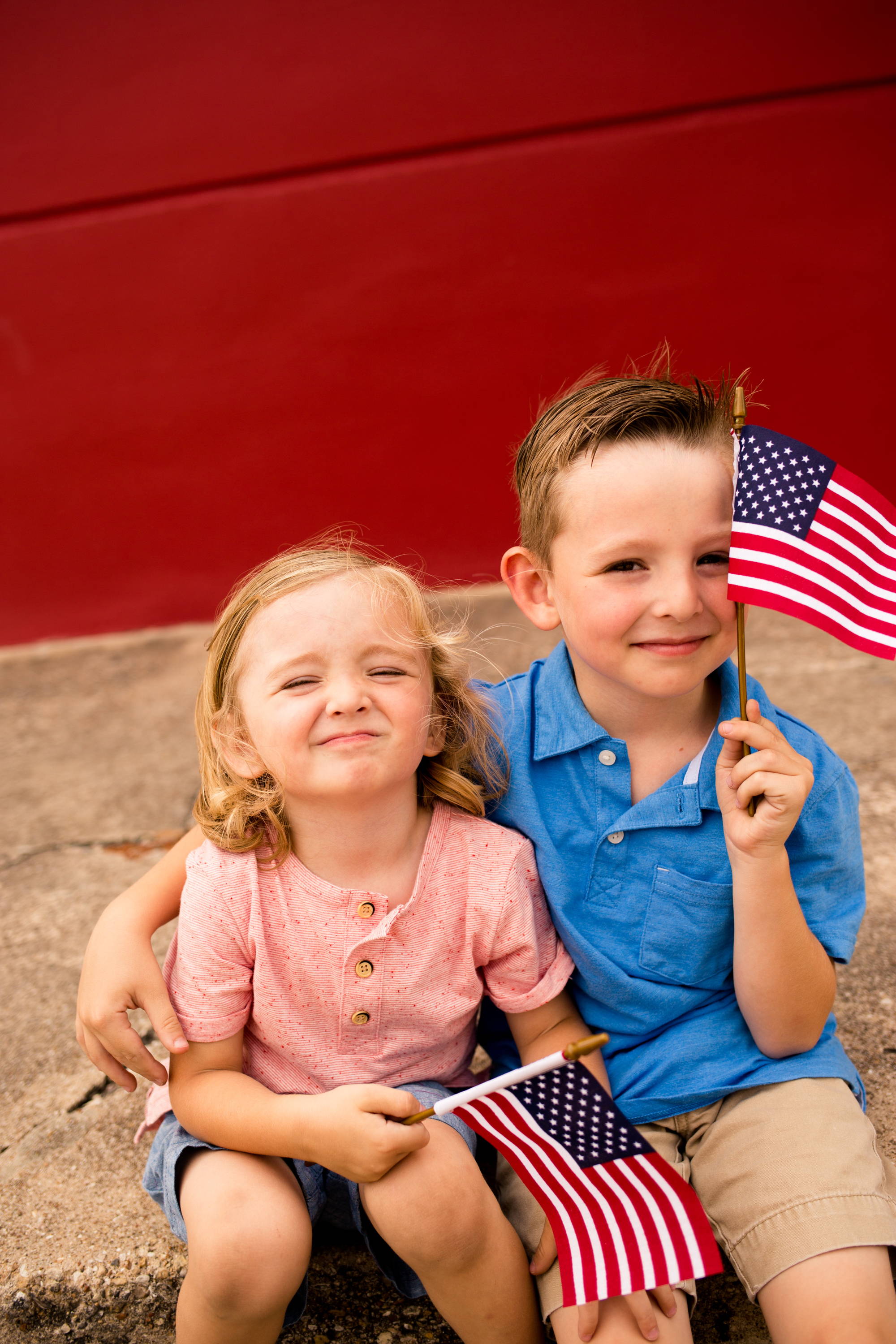 little boy and girl holding miniature American flags, smiling, happy, Fourth of July celebration