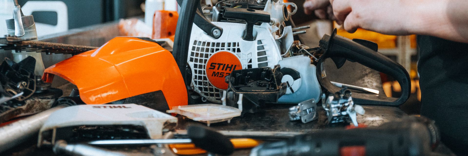 Tools and equipment on a workbench, including a chainsaw and various parts.