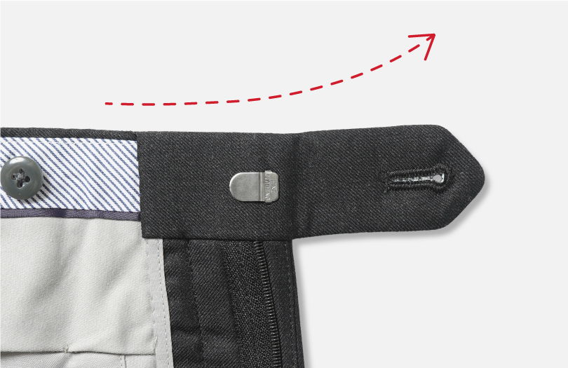 Close-up of a clothing fastener with a dotted arrow indicating movement.