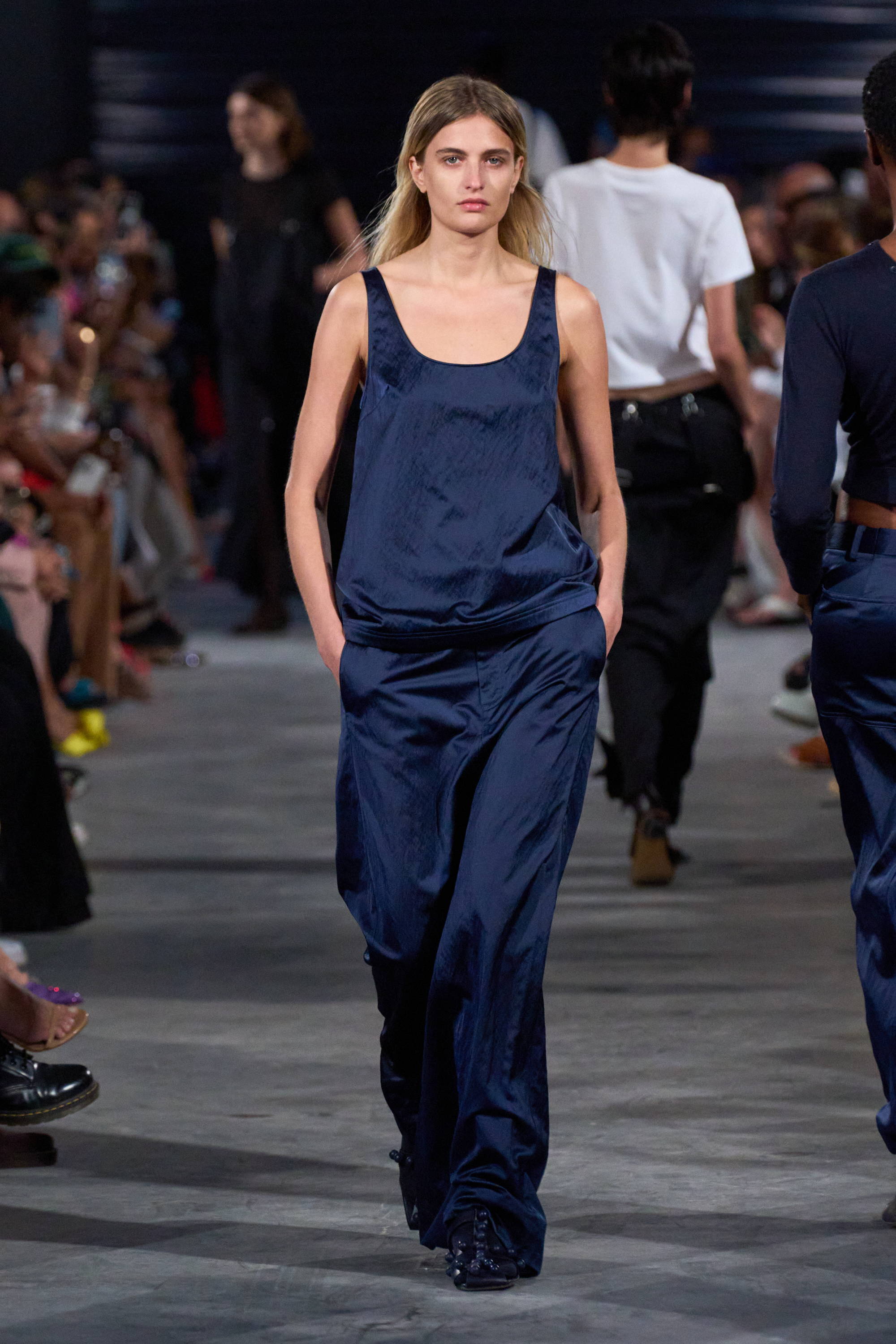 Model on a runway wearing tank top and pants