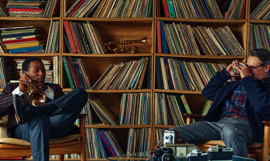 Two people sitting in a room filled with vinyl records.