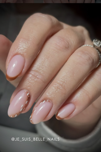 A hand with elegantly manicured pink nails and a ring.