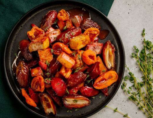 A plate of colorful roasted vegetables garnished with herbs.