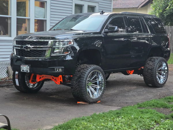 Front three-quarter view of Theo's lifted black 2018 Chevy Tahoe with bright orange suspension components, install photo 1