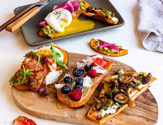 Three colorful pizza slices served on a wooden platter with garnishes.