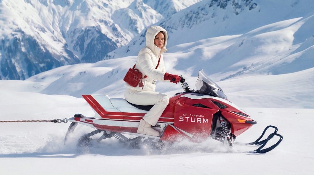 A person riding a snowmobile through snowy mountains.
