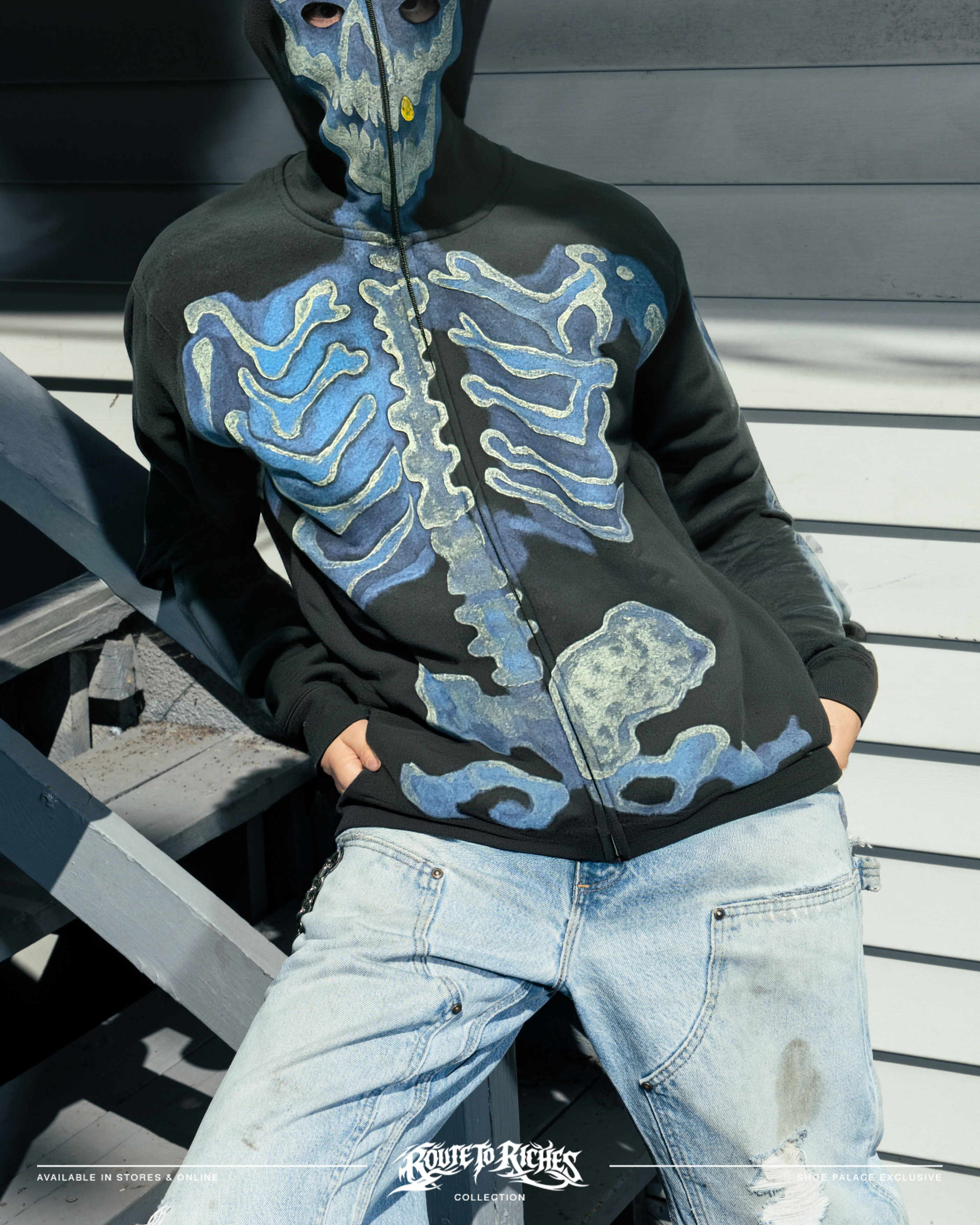 Person wearing a skeleton-printed hoodie and distressed jeans.