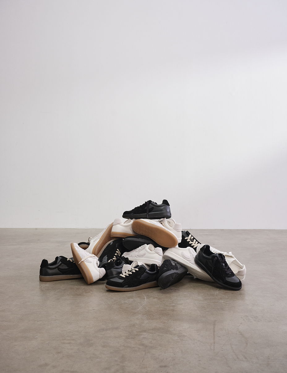 A pile of various sneakers on a concrete floor.