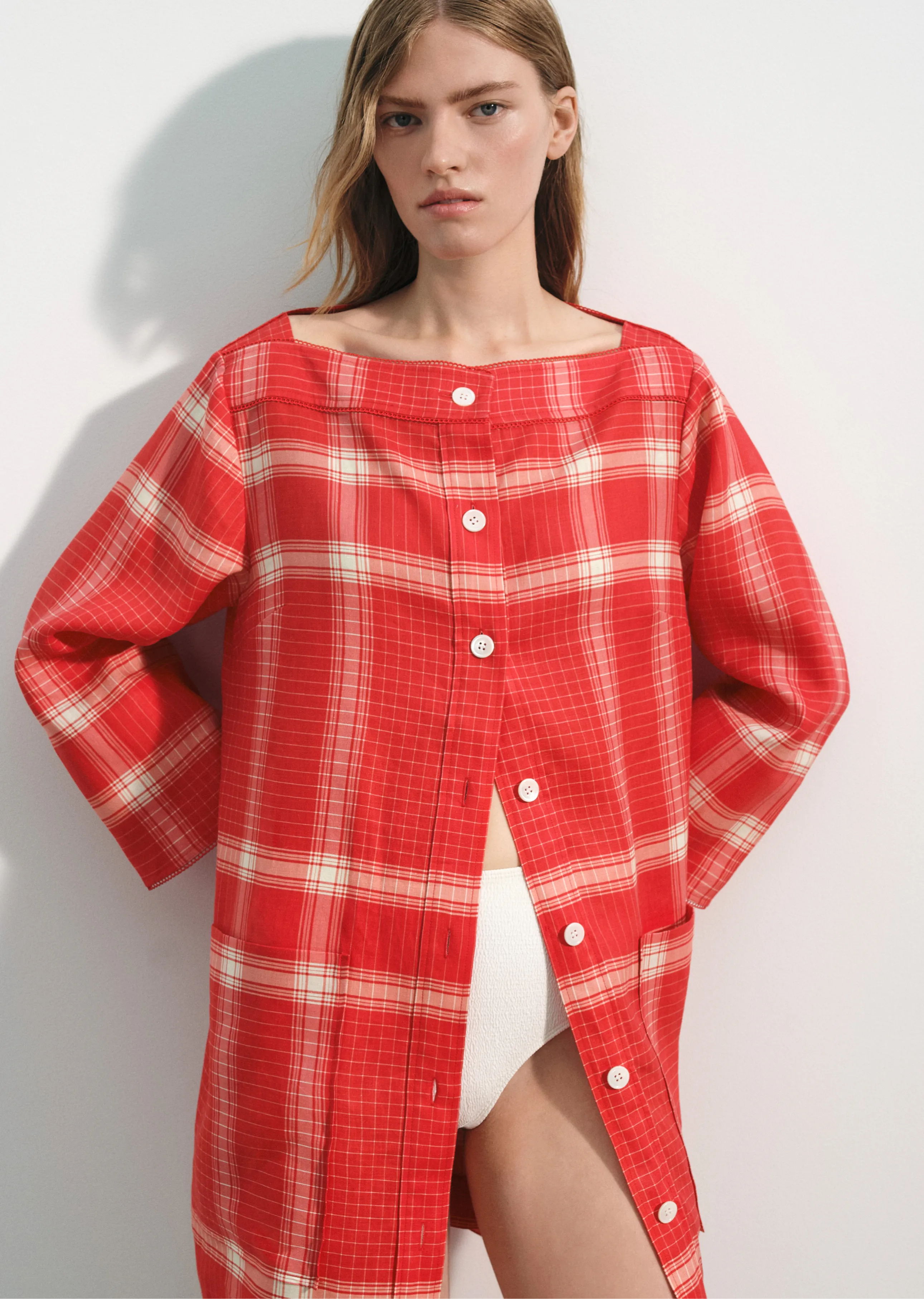 Model wearing a red plaid oversized shirt with buttons.