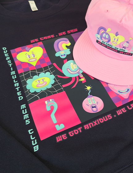 Pink surf cap sitting on an indigo blue t-shirt printed with a colourful retro-style graphic