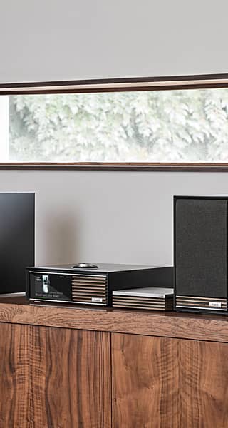 Modern audio equipment on a wooden shelf with a window in the background.
