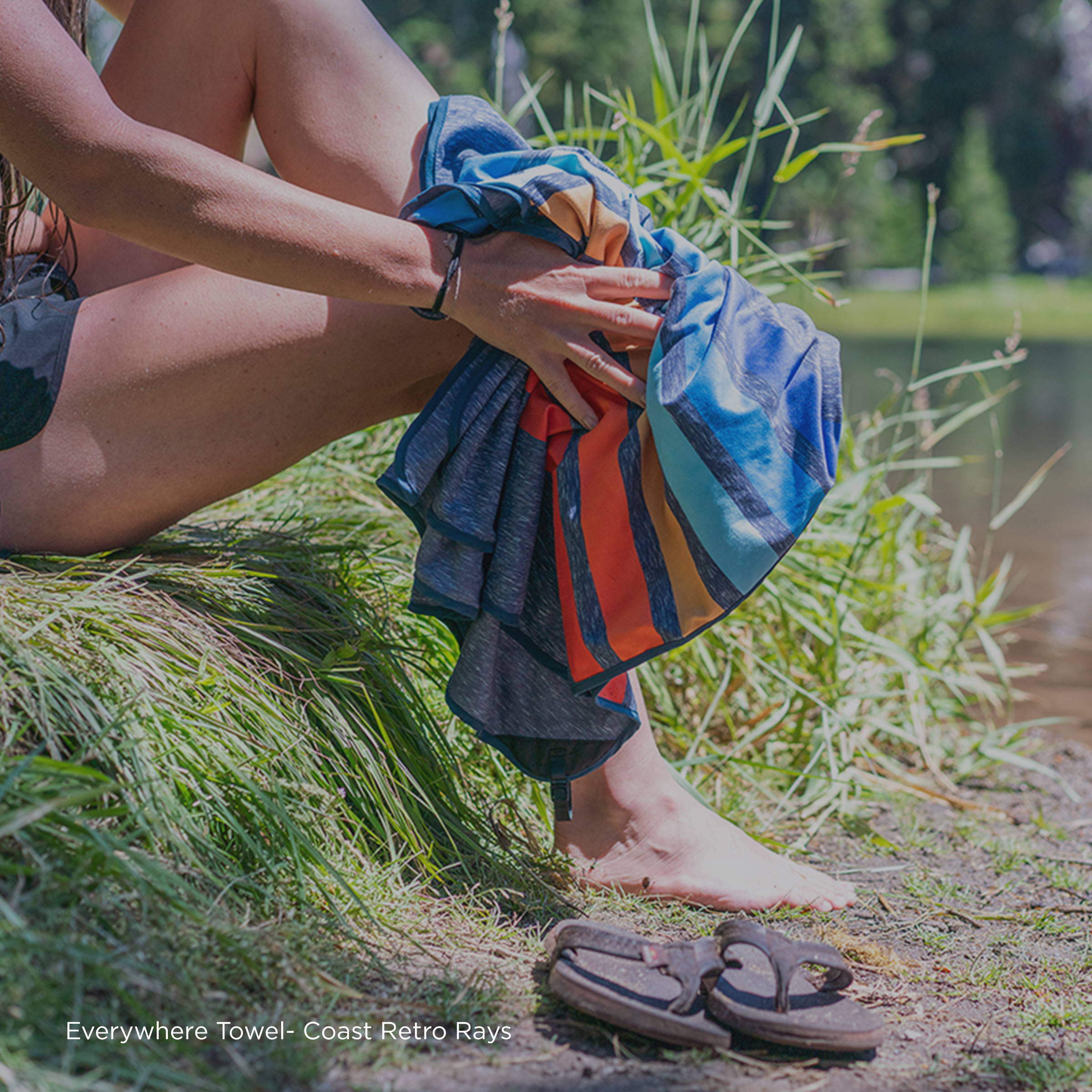 Person drying off feet next to a river with a Rumpl Everywhere Towel