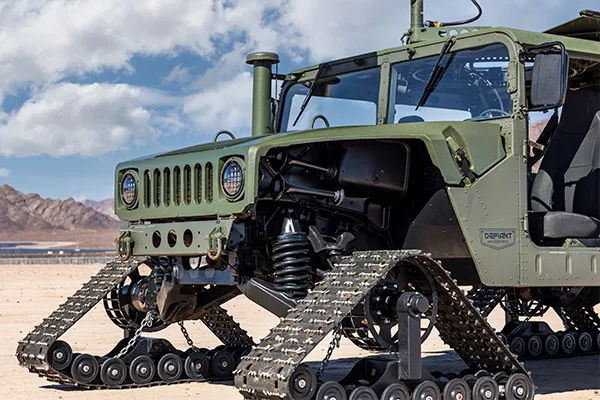 Front three-quarter tracked Humvee coil-over shock black treads Defiant Motorsports badge desert mountains Prodigy TV Warship KM-110 gallery photo 2