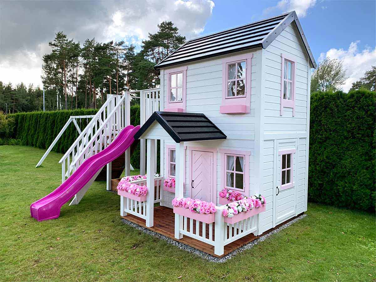 2- Story white Outdoor Playhouse Princess with pink fishbone door and window trims and pink flower boxes in the backyard by WholeWoodPlayhouses