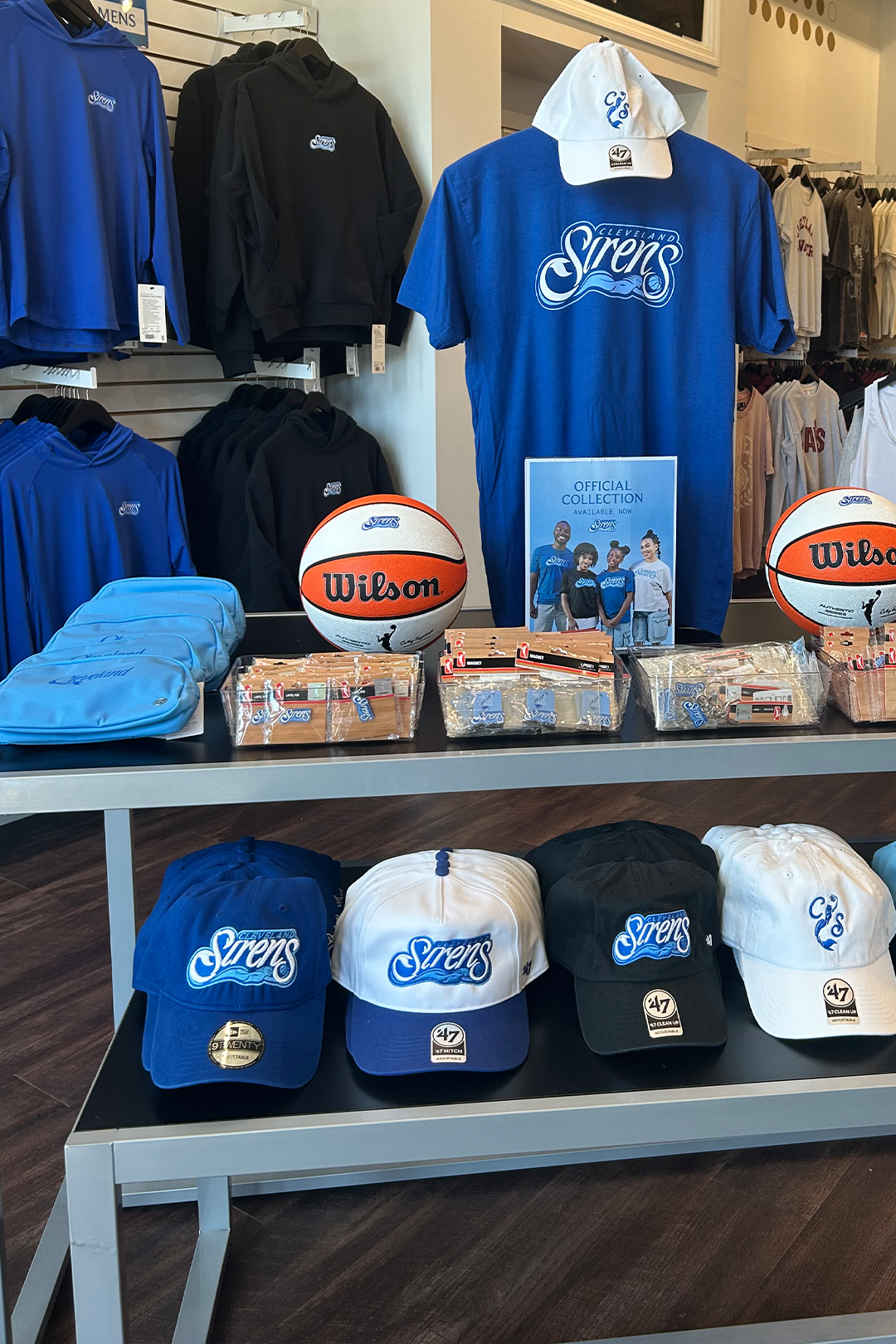 Merchandise display with apparel, hats, and basketballs on a table.