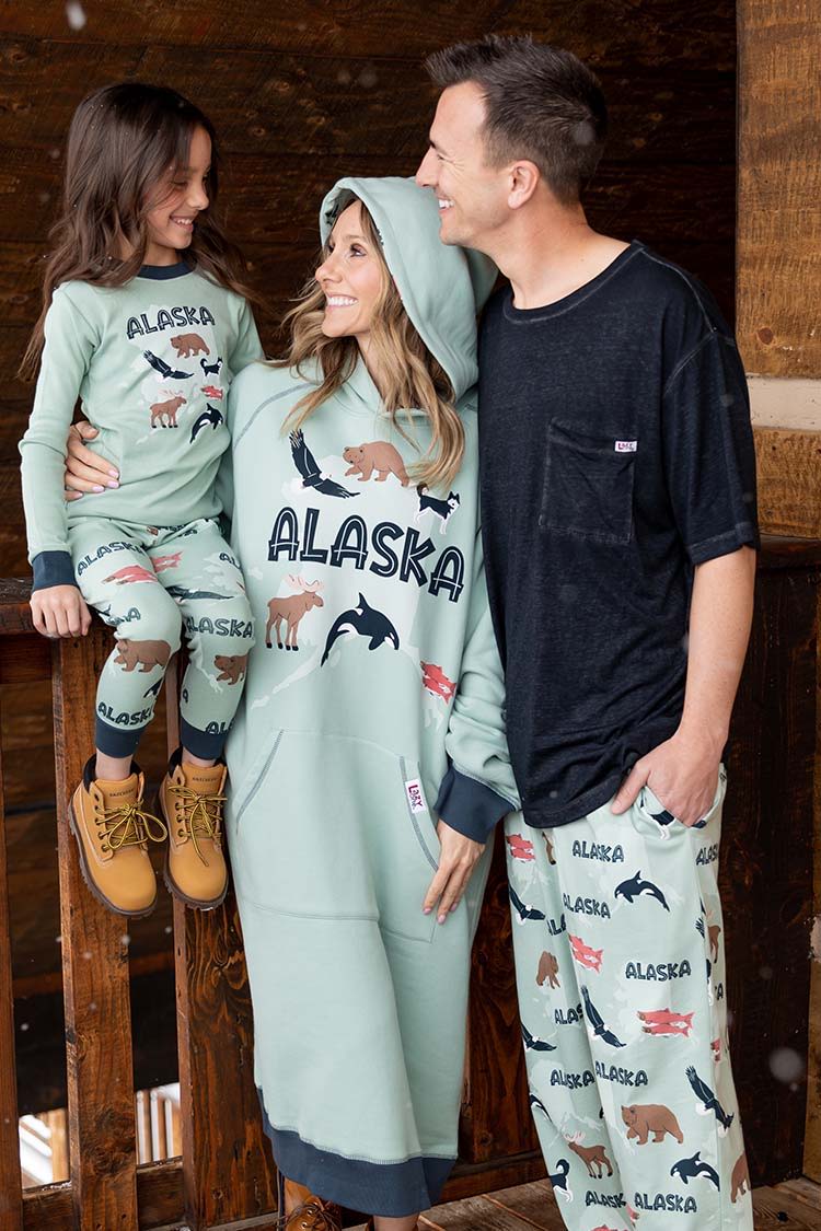 Family in matching Alaska-themed pajamas, posing indoors.